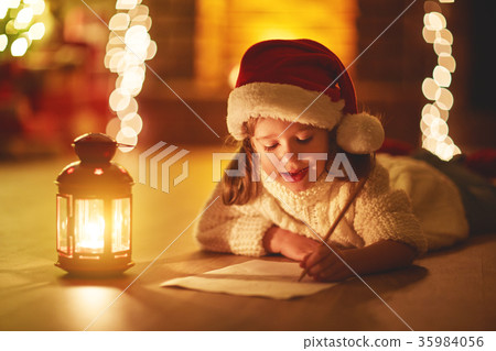 child girl writing letter santa home near Christmas tree 35984056
