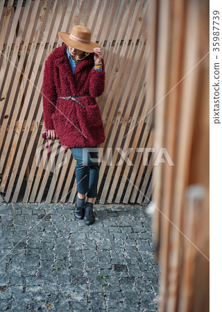 Confident blond lady standing near wood palisade Confident blond lady standing near wood palisade 35987739