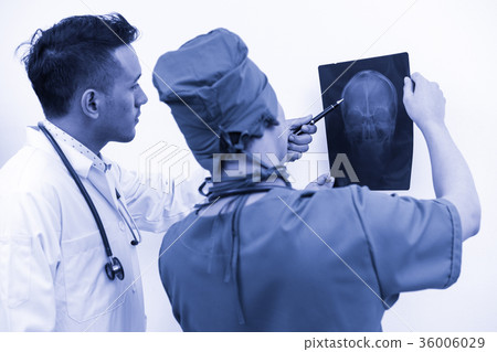 Doctors looking at x-ray film of patient 's head Doctors looking at x-ray film of patient 's head 36006029