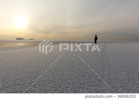 Man standing on  ice of a freezing pond  36008203