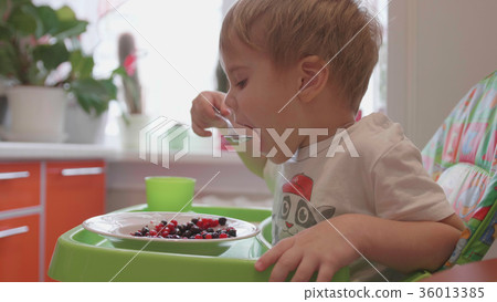 The child sits at the table and eats a spoonful of The child sits at the table and eats a spoonful of 36013385
