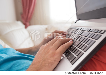 Man's hands typing on laptop notebook keyboard at 36014654