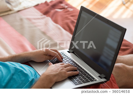 Man's hands typing on laptop notebook keyboard at 36014658
