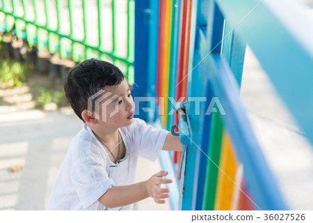 Sad Asian kid behind the grid trying to escape. 36027526