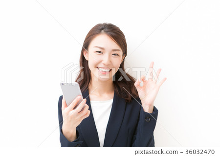 A woman holding a smartphone and making an okay sign 36032470