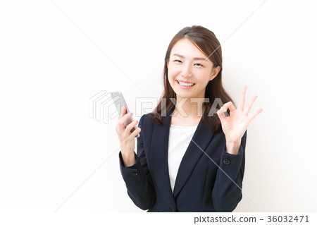 A woman holding a smartphone and making an okay sign 36032471