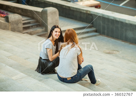 Two cheerful girls sitting on the stairs 36032767