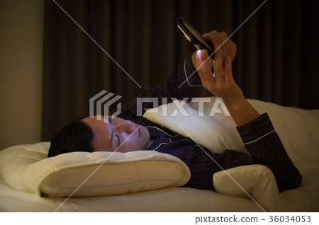年輕人在床上觀看智能手機 36034053