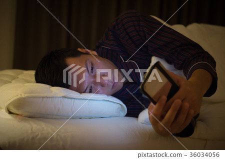 年輕人在床上觀看智能手機 36034056