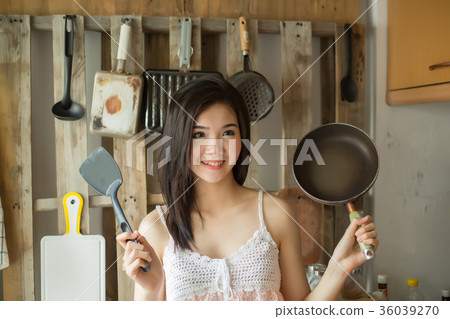 Smile Asian girl in is holding pan the kitchen. Smile Asian girl in is holding pan the kitchen. 36039270