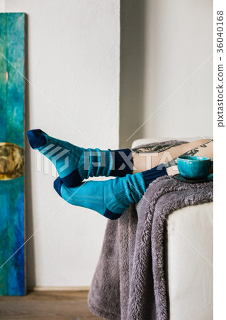 Feet in woollen. Woman relaxes with a cup of hot 36040168