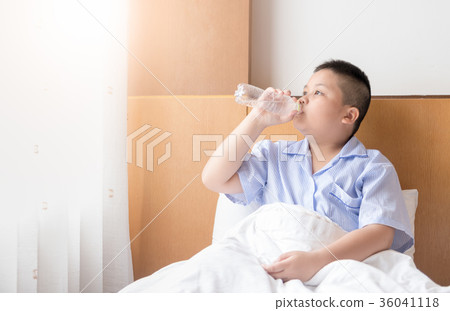 Obese fat boy drinking water on bed in morning 36041118