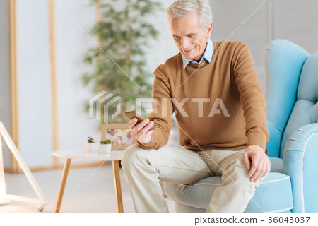 Happy senior man smiling while reading message Happy senior man smiling while reading message 36043037