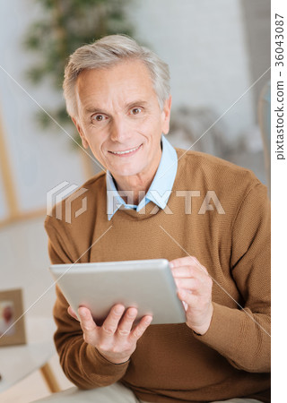 Positive minded elderly man enjoying working on Positive minded elderly man enjoying working on 36043087