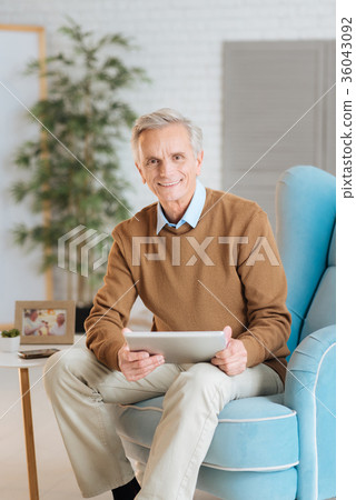 Friendly looking old gentleman working on tablet Friendly looking old gentleman working on tablet 36043092