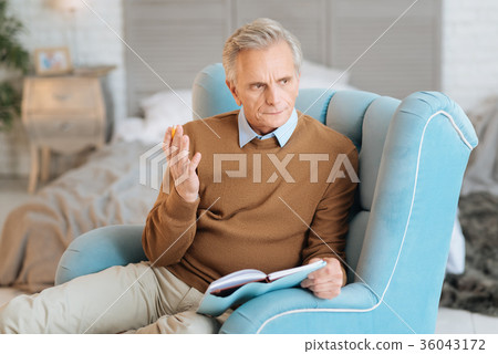 Pensive senior gentleman gesturing while writing 36043172