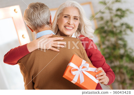 Radiant lady grinning broadly and hugging her 36043428