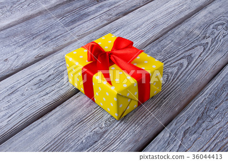Beautiful yellow gift box with a red ribbon. 36044413