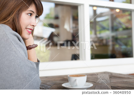 woman sit in cafe with hot cappuccino coffee on wood table during brunch. asian female have a break in coffee shop. 36048950