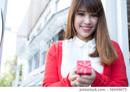 woman holding gift box. asian female wear white shirt and red knitting cardigan with present box. christmas, new year, birthday, valentine, celebration concept. 36049075