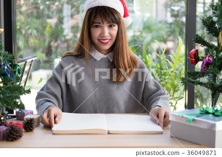 asian woman wear santa claus hat at home. girl with notebook, gift present box, christmas tree. xmas, new year celebration. season greetings asian woman wear santa claus hat at home. girl with notebook, gift present box, christmas tree. xmas, new year celebration. season greetings 36049871