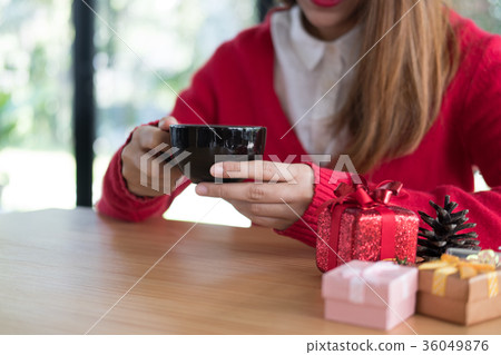 woman wear red sweater with gift box on table at restaurant. girl hold latte coffee cup at cafe. christmas, new year celebration woman wear red sweater with gift box on table at restaurant. girl hold latte coffee cup at cafe. christmas, new year celebration 36049876