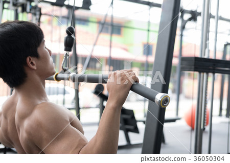 young man execute exercise with weightlifting machine in fitness center. male athlete pump up muscle with pull down machine in gym. sporty guy working out in health club. young man execute exercise with weightlifting machine in fitness center. male athlete pump up muscle with pull down machine in gym. sporty guy working out in health club. 36050304