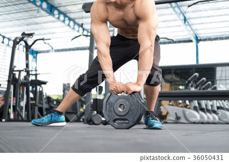 young man bodybuilder execute exercise in fitness center. male athlete lift heavy weight barbell plate in gym. sporty guy working out in health club. young man bodybuilder execute exercise in fitness center. male athlete lift heavy weight barbell plate in gym. sporty guy working out in health club. 36050431