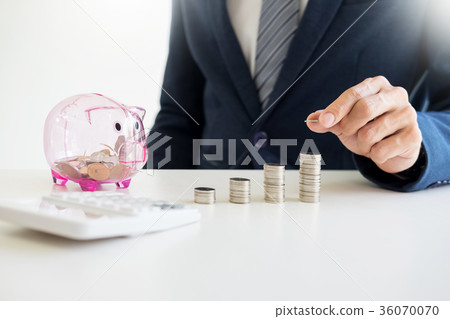 Close up of Businessman putting coin into small piggy bank , The Close up of Businessman putting coin into small piggy bank , The 36070070