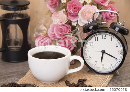 Hot cup of coffee and alarm clock on wood table  36070958