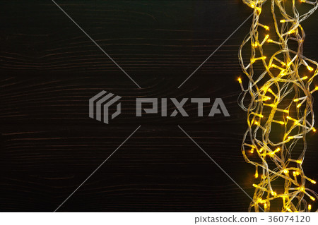 Christmas lights border on dark wooden background Christmas lights border on dark wooden background 36074120