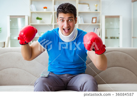 Man with neck injury watching boxing at home 36084587