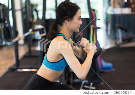 Side view of young beautiful woman in sportswear doing squat wit Side view of young beautiful woman in sportswear doing squat wit 36095034