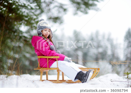 Funny little girl having fun with a sleight in winter park 36098794