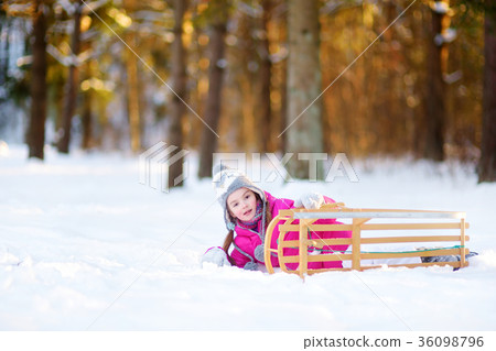 Funny little girl having fun with a sleight in winter park 36098796