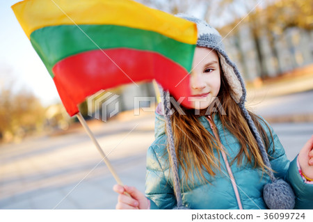 Cute little girl celebrating Lithuanian Independence Day holding tricolor Lithuanian flags 36099724