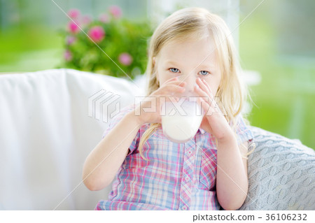 Cute little girl drinking fresh organic milk at sunny summer day Cute little girl drinking fresh organic milk at sunny summer day 36106232