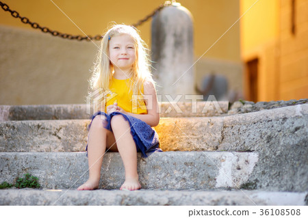 Adorable little girl sitting on the stairs on warm and sunny summer day 36108508
