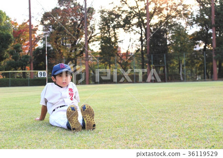 Baseball boy (infant) sitting on the ground at dusk 36119529