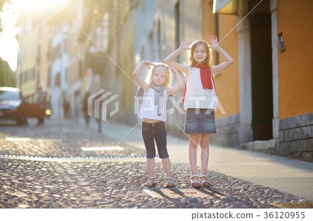 Two adorable little sisters having fun together on summer evening in Desenzano del Garda 36120955
