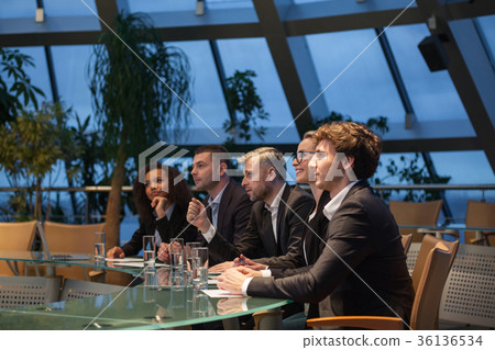 A group of business people sit at a table in a A group of business people sit at a table in a 36136534