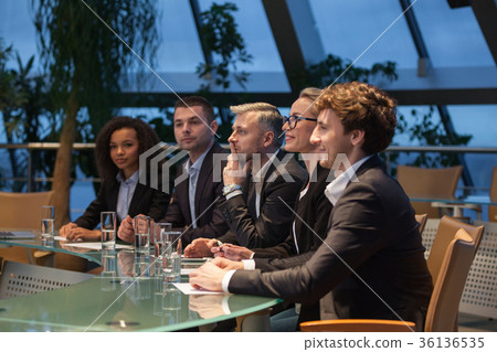 A group of business people sit at a table in a A group of business people sit at a table in a 36136535