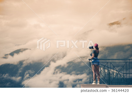 A female photographer with a camera on the balcony 36144420
