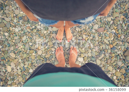 Young woman and boy standing on a rounded pebble 36158099