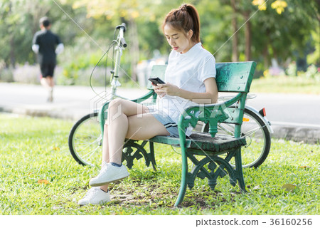 Woman relaxing on park bench under a tree  36160256