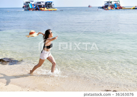 Beautiful woman wearing a swimsuit playing in the beach. Beautiful woman wearing a swimsuit playing in the beach. 36163076