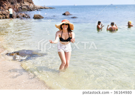 Beautiful woman wearing a swimsuit playing in the beach. Beautiful woman wearing a swimsuit playing in the beach. 36164980