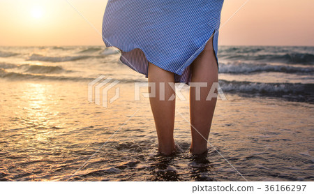 Girl walking towards water at sunset 36166297