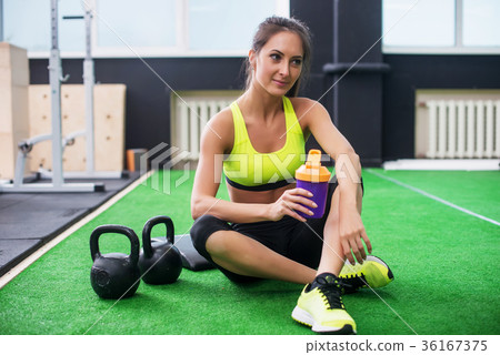 young sporty woman drinking water in gym, holding young sporty woman drinking water in gym, holding 36167375