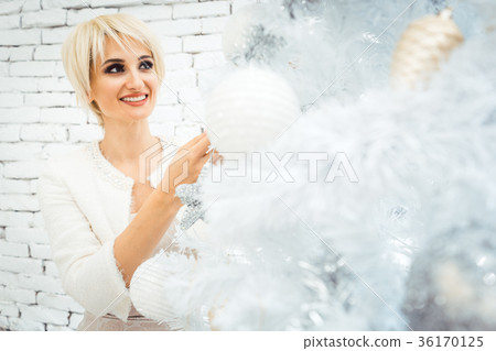 Woman decorating white and gold Christmas tree 36170125